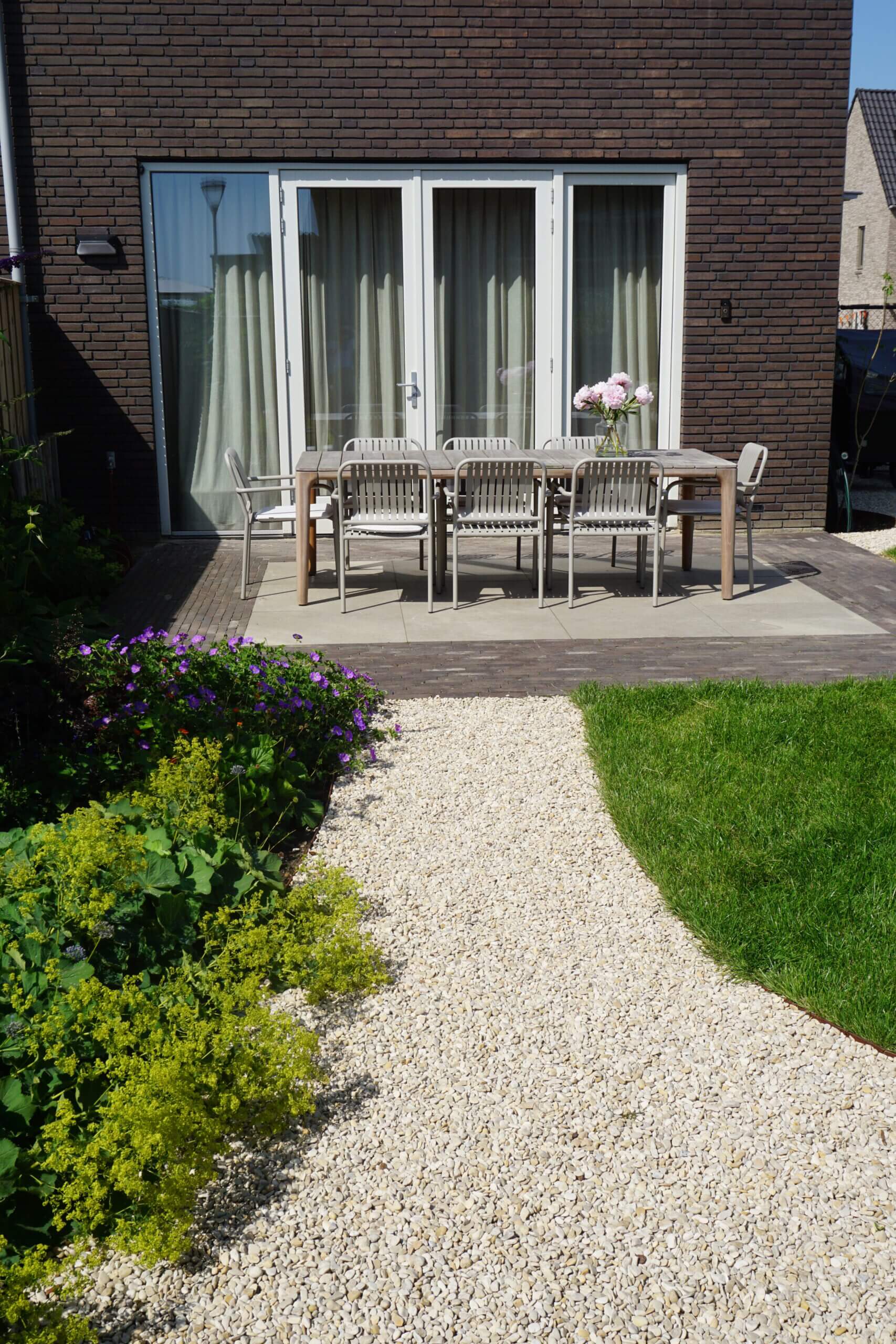 Tuintegels combineren met grind, gras of houten vlonders
